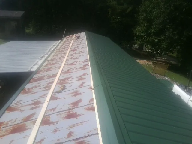 Old rusted panels beside newly installed green metal roofing — Wind Damage Roof Repair by Roofing Brothers in Horseshoe Beach