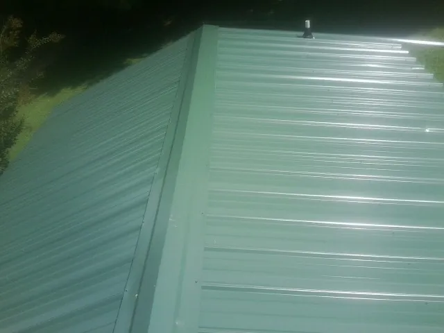 New green metal panels meeting at the ridge of a roof — Flat Roof Repair work by our crew in Horseshoe Beach