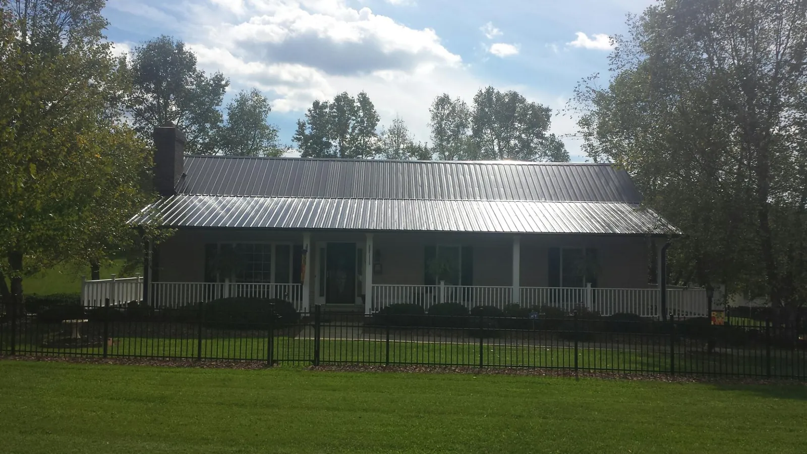 Gray metal roof on a brick ranch with a full width front porch — Gutter Guard Installation work by our crew in Horseshoe Beach