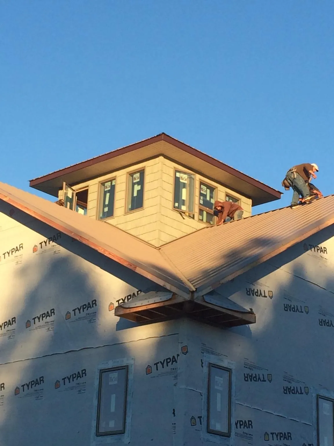 Roofers working around a rooftop cupola on a new metal roof at sunset — Roof Waterproofing in Horseshoe Beach by Roofing Brothers